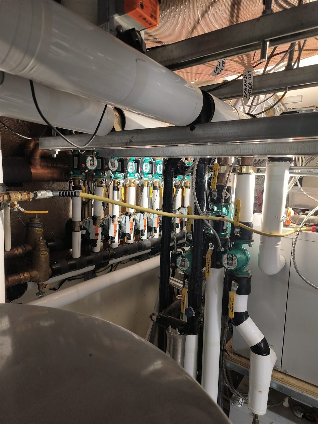 Circulating pumps, isolation valves and insulated headers in a commercial mechanical room.